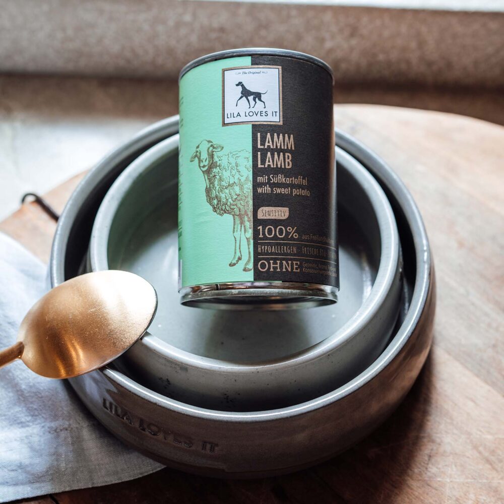 Dose Nassfutter für Hunde aus Lammfleisch demonstrativ in Futternapf platziert auf einem hellen Holz-Hintergrund mit Bronzelöffel | LILA LOVES IT "Nassfutter aus Lamm"